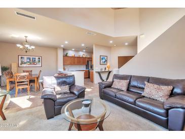 Bright and airy living room with leather furniture and an open floor plan to the dining area and kitchen at 3131 E Legacy Dr # 1104, Phoenix, AZ 85042