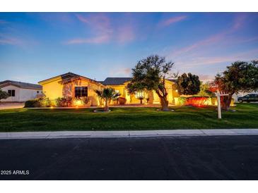 Inviting single-story home with lush landscaping, enhanced by warm exterior lighting at dusk at 3531 E Norwood Cir, Mesa, AZ 85213