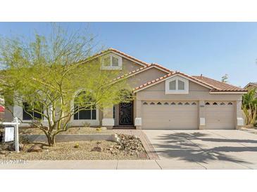 Charming single-story home featuring a three-car garage, desert landscaping, and a tile roof at 5310 W Melinda Ln, Glendale, AZ 85308