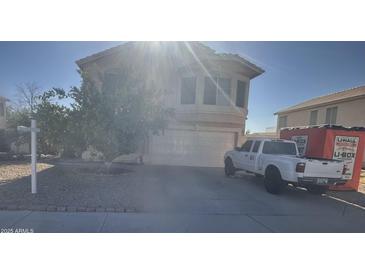 Beige two-story home featuring an attached two-car garage, desert landscaping, and a U-Haul moving container at 8863 W Greer Ave, Peoria, AZ 85345