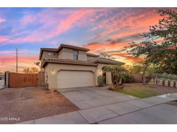 Charming two-story home featuring stucco siding, tile roof, and a two-car garage, set against a colorful sunset sky at 11965 W Monte Vista Rd, Avondale, AZ 85392