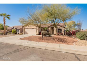 Charming single-story home featuring a well-manicured yard with mature trees and a two-car garage at 13208 W Desert Rock Dr, Surprise, AZ 85374