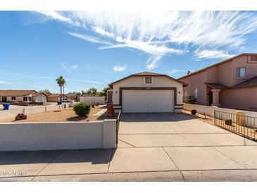 Charming single-story home featuring a well-maintained front yard and a two-car garage at 14957 W Bottle Tree Ave, Surprise, AZ 85374