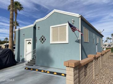 Charming single-story home with a light blue exterior, complemented by a well-maintained yard and palm trees at 2315 S Seminole Dr, Apache Junction, AZ 85119