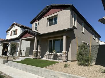 Charming two-story home featuring a quaint front yard with artificial turf and a cozy outdoor seating area at 475 S Soho Ln # 35, Chandler, AZ 85225