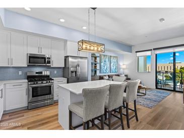 Modern kitchen featuring a central island, stainless steel appliances, and a view into the living area at 7300 E Earll Dr # 3016, Scottsdale, AZ 85251