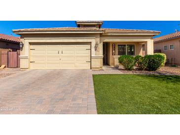 Charming single-story home featuring a two-car garage, brick driveway, and well-manicured lawn at 828 W Leadwood Ave, San Tan Valley, AZ 85140