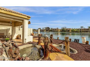 Backyard with a pond, fountain, small bridge, covered patio, and a lake view at 9019 W Acoma Dr, Peoria, AZ 85381