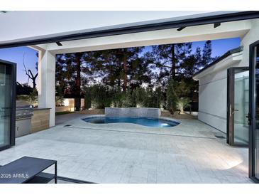 A luxurious outdoor space features a modern pool with integrated waterfall and an outdoor kitchen, creating an ideal entertainment space at 11578 N 80Th Pl, Scottsdale, AZ 85260