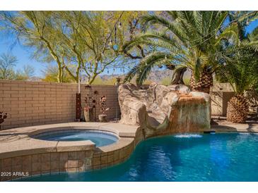 Sparkling pool with rock waterfall, slide, spa, and lush desert landscaping, perfect for relaxing and entertaining at 16256 S 1St St, Phoenix, AZ 85048