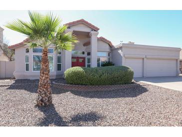 Charming single-story home with a well-manicured lawn, desert landscaping, and a vibrant red front door at 1915 E Citation Ln, Tempe, AZ 85284