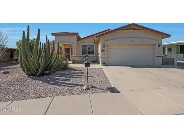 Charming single-story home featuring desert landscaping, a two-car garage, and a cozy front patio with seating at 2416 N Snead Dr, Mesa, AZ 85215