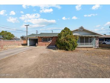 Charming single-story home with a brick facade, green roof, spacious front yard and attached garage at 4020 W Tuckey Ln, Phoenix, AZ 85019
