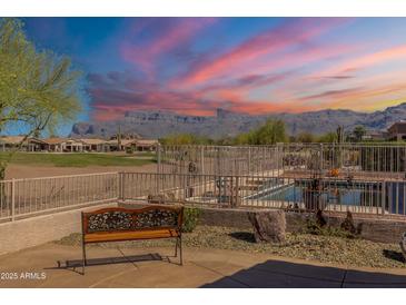 Expansive backyard featuring a bench, private pool, and stunning mountain views at sunset at 6620 S Front Nine Dr, Gold Canyon, AZ 85118