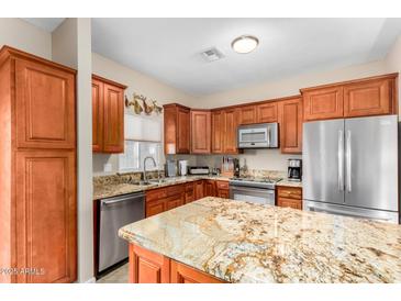 Well lit kitchen with an island, stainless steel appliances, granite countertops, and wood cabinets at 1600 N Saba St # 191, Chandler, AZ 85225