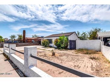 Charming single-story home with white stucco walls, fence and desert landscaping under a partly cloudy sky at 3129 W Pierce St, Phoenix, AZ 85009