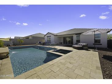 A stunning backyard pool with a spa and patio area, perfect for entertaining at 38162 W Santa Monica Ave, Maricopa, AZ 85138