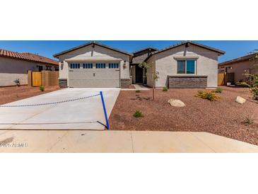 Inviting single-Gathering home features desert landscaping, neutral stucco and a two car garage at 8553 N 175Th Ln, Waddell, AZ 85355