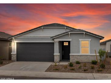 Charming single-story home with gray stucco, well-manicured landscaping and beautiful sunset backdrop at 8554 W Trenton Ct, Florence, AZ 85132
