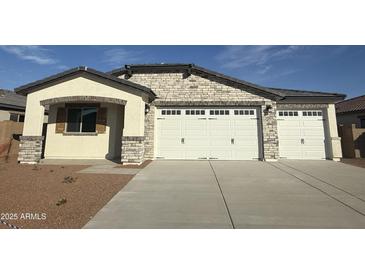 Charming exterior view of the house with a three-car garage and well-maintained desert landscaping at 8561 N 175Th Ln, Waddell, AZ 85355