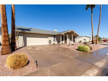 Charming single-story home with a two-car garage, desert landscaping, and mature palm trees at 11830 S Paiute St, Phoenix, AZ 85044