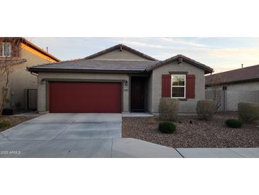 Charming single-story home featuring a red garage door and desert landscaping at 13487 W Buckskin Trl, Peoria, AZ 85383