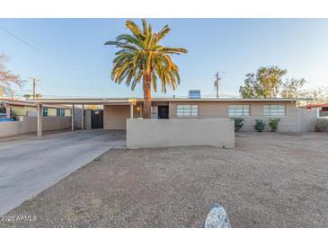 Charming single-story home featuring a desert landscape, large palm tree, and attached carport at 3611 W Hazelwood St, Phoenix, AZ 85019