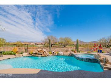 Backyard pool with waterfall feature and jacuzzi offers a tranquil outdoor space with desert views at 40607 N Candlewyck Ln, Phoenix, AZ 85086