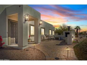 Charming outdoor space with brick pavers, outdoor fireplace, and seating, perfect for evening relaxation and entertaining at 6440 E Jean Dr, Scottsdale, AZ 85254