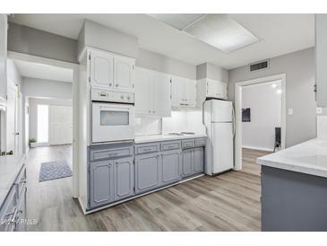 Traditional-style kitchen with white cabinets and oven range, grey lower cabinets, and wood-look flooring at 713 E Eason Ave, Buckeye, AZ 85326