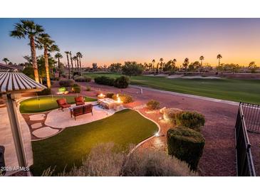 Outdoor living space with a putting green, fire pit, and views of the golf course at 22020 N San Ramon Dr, Sun City West, AZ 85375