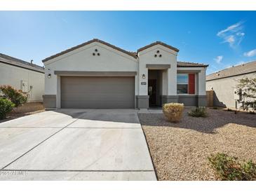 Charming single-Gathering home features a neutral color palette, a two-car garage, and low maintenance landscaping at 30747 W Indianola Ave, Buckeye, AZ 85396