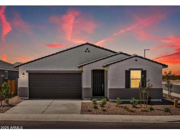 Charming single-story home featuring stucco, a two-car garage, and a desert-landscaped front yard under a colorful sunset sky at 3864 N Camden Dr, Florence, AZ 85132