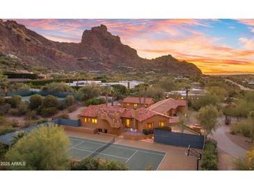 Desert home featuring a tennis court and mountain views during a colorful dusk sky at 5567 E Mcdonald Dr, Paradise Valley, AZ 85253