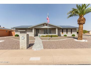 Charming home with desert landscaping, complemented by a mature palm tree and solar panels at 6456 E Dallas St, Mesa, AZ 85205