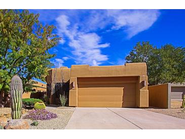 Charming stucco home with a two-car garage, desert landscaping and a concrete driveway at 9576 E Kiisa Dr, Scottsdale, AZ 85262