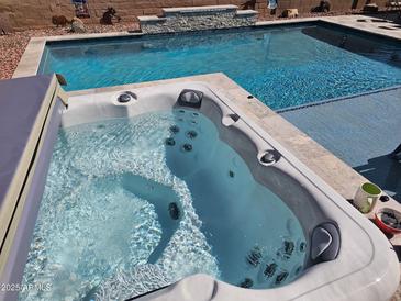 Inviting backyard features a sparkling pool and a relaxing hot tub, perfect for outdoor enjoyment and leisure at 21432 W Minnezona Ave, Buckeye, AZ 85396