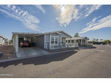 Inviting exterior view of home with carport, white fencing, and landscaped surroundings on a sunny day at 2206 S Ellsworth Rd # 50B, Mesa, AZ 85209