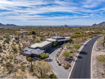 Stunning aerial shot of desert home, showcasing the home's design, long driveway, and natural surroundings at 8145 E Tecolote Cir, Scottsdale, AZ 85266