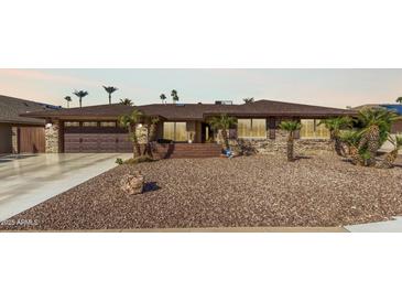 Charming single-story home boasts a brick facade, desert landscaping, and a two-car garage at 11010 W Acacia Dr, Sun City, AZ 85373