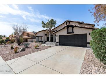 Charming single-story home featuring a desert landscape, a two-car garage, and black trim accents at 14820 N 44Th Pl, Phoenix, AZ 85032