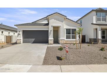 Charming single-Gathering home features a gray garage door, stone accents, and low-maintenance landscaping at 17819 W Mission Ln, Waddell, AZ 85355