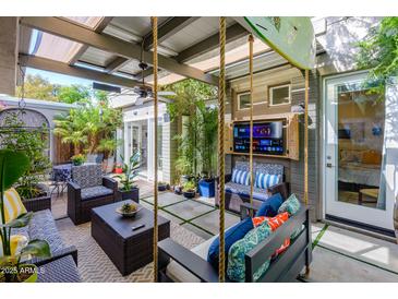 Inviting outdoor living space with comfortable seating, a TV, tropical plants, and a unique hanging swing at 5205 N 8Th Pl, Phoenix, AZ 85014