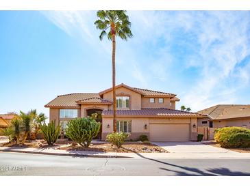 Charming two-story home with a desert landscape, palm tree, and tile roof at 6105 W Kimberly Way, Glendale, AZ 85308