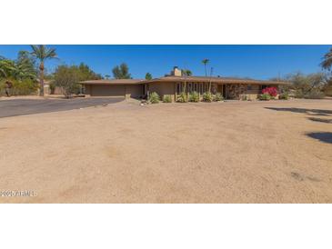 Tan single story home with well-manicured landscaping, stone accents, and a circular driveway at 7102 E Larkspur Dr, Scottsdale, AZ 85254