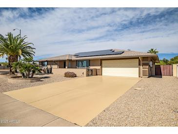 Single story home featuring desert landscaping, solar panels and a large driveway at 12530 W Skylark Dr, Sun City West, AZ 85375