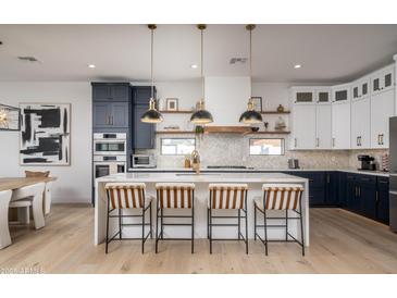 Stunning kitchen with a large waterfall island, stylish pendant lights, and modern two-tone cabinetry at 3628 E Clarendon Ave, Phoenix, AZ 85018