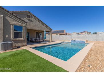 Backyard view of a refreshing pool with a waterfall feature and an outdoor dining area at 3973 N 310Th Ln, Buckeye, AZ 85396