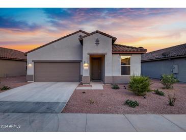 Charming single-story home with a well-maintained front yard and attached two-car garage at sunset at 42195 W Lavender Dr, Maricopa, AZ 85138