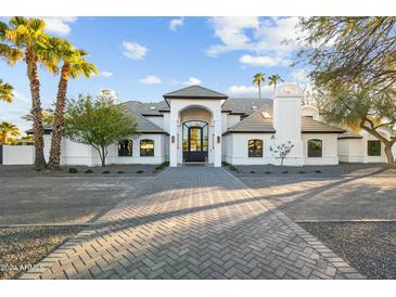 Stunning two-story home featuring a circular driveway and lush palm trees in a luxurious community at 5601 E Caballo Dr, Paradise Valley, AZ 85253